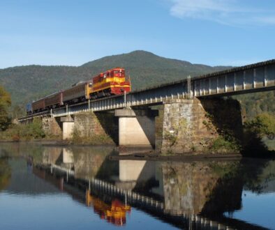 a2ab4405-5ad9-4bab-96b7-03547e0a1810-mirrored-train-crossing-hiwassee-river-mountain-in-backgroun