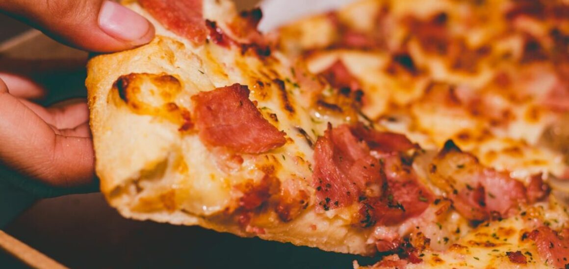 close up photo of person holding pizza