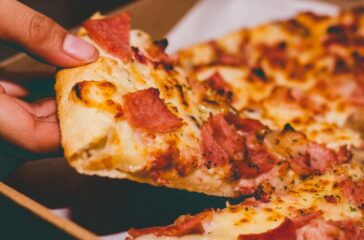 close up photo of person holding pizza