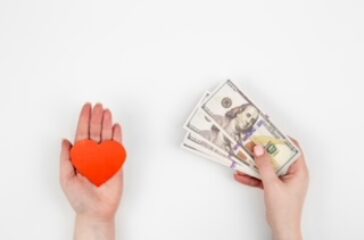 Hand with paper heart and a gift box on a white background isolated, flat lay.