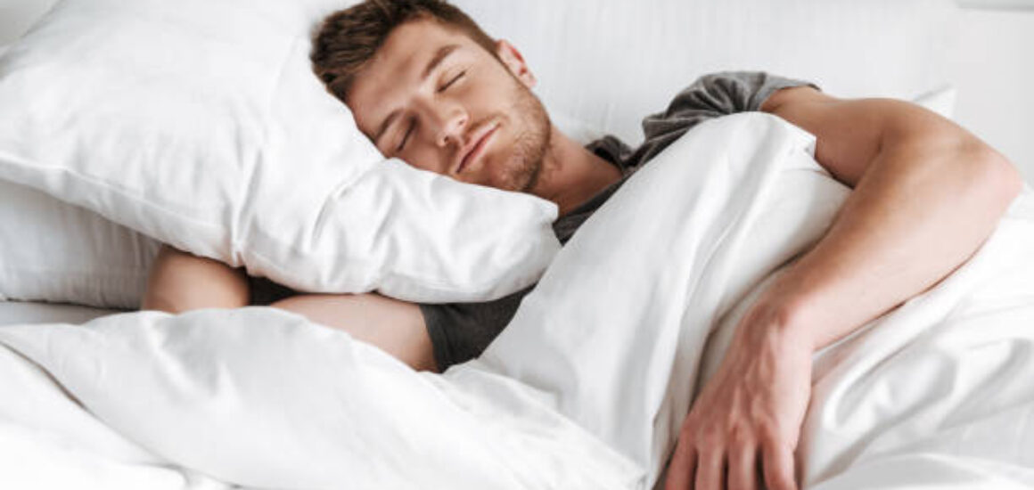 Handsome young man sleeping in bed at home