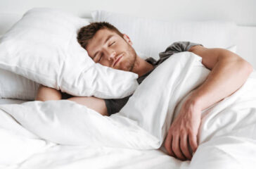 Handsome young man sleeping in bed at home