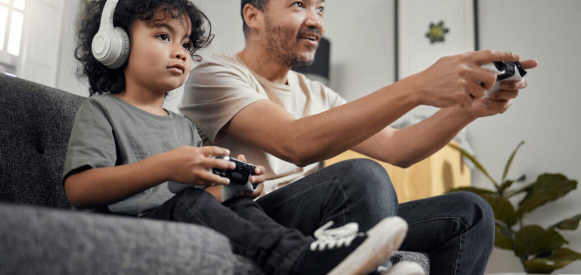 Shot of an adorable little boy and his father playing video games at home.